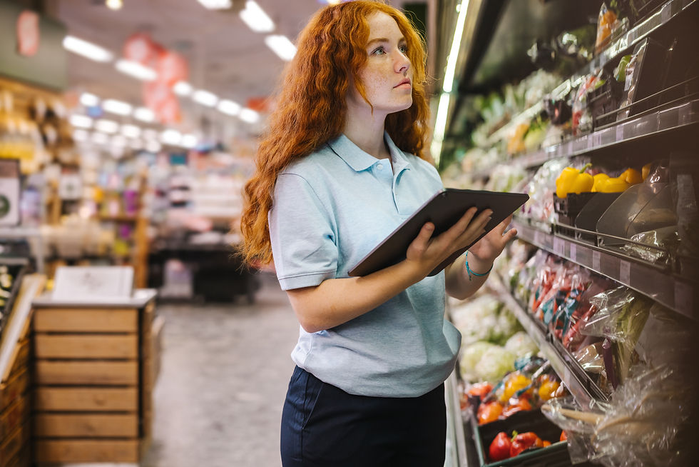 A female supermarket employee is doing a stock check in the produce section.