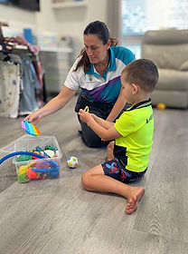 oung boy communicating with an allied health professional during a therapy session.