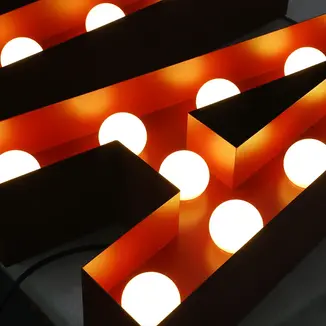 Close-up of luminous letter signs with marquee bulbs.