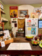 Cozy cafe counter with vintage posters, menu displaying organic coffee prices. Green bowls and fruit decor add a homey touch.