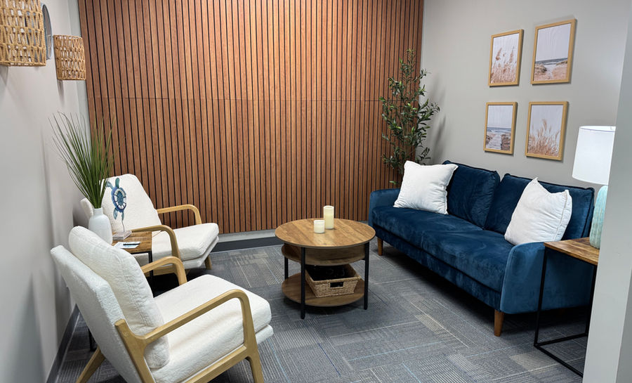 Open meeting room featuring a dark blue couch and two chairs.