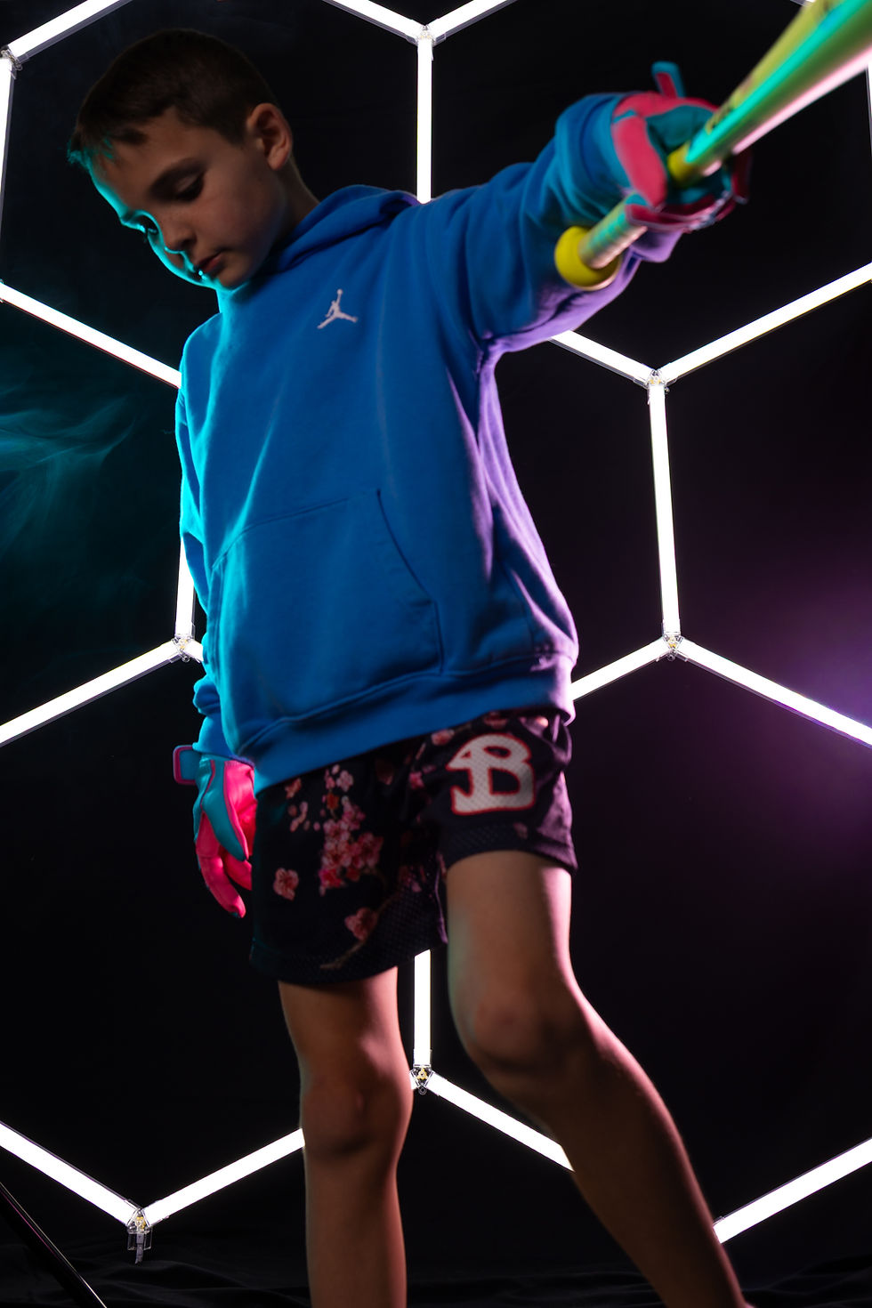 A youth baseball player stands in front of LED lights