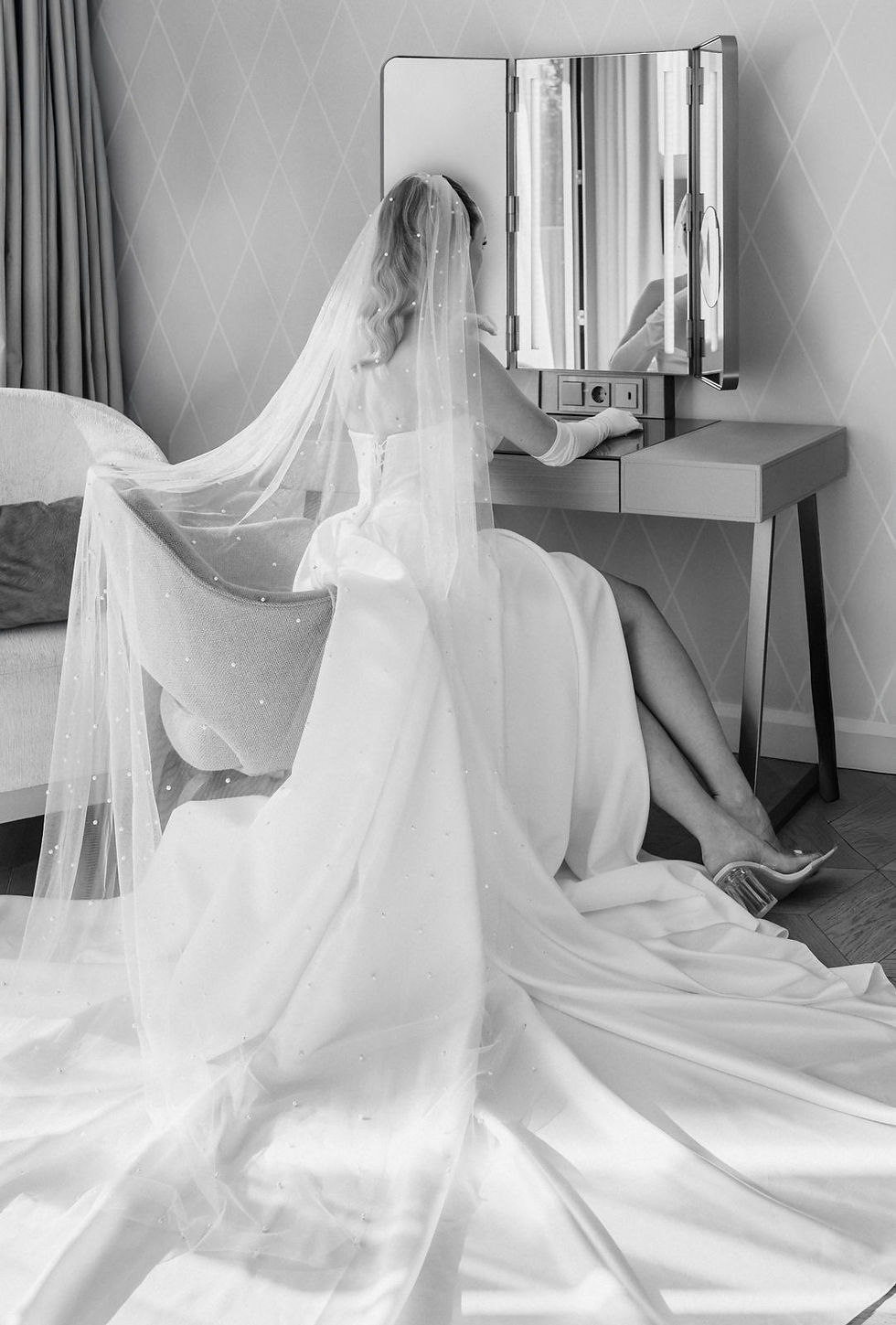 Braut mit langem Schleier am Hochzeitstag am Schminktisch im Hotelzimmer