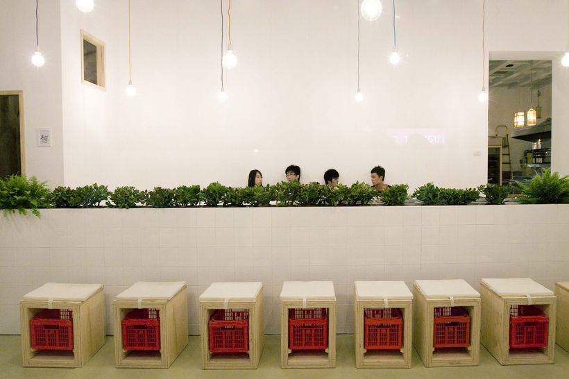 It is a project for the renovation of an existing Chinese restaurant. The idea was to create a Chinese restaurant different from the imaginary, recovering some typical elements of Chinese culture, avoiding clichés.A place where you can meet Italian and Chinese people eating together and sharing good food.The image of the restaurant is the typical way of eating the Chinese: outside their homes, sitting on baskets and lights hanging from the trees, is the attempt to introduce this moment of sociality in  
Milan.
The concept is to maintain a continuity between inside and outside so that people are encouraged to enter: creating a single room (before it was divided by a central wall) visible from the outside through the windows, which creates an internal square, surrounded from homes, as the volume of the bath conceived with the shape of a house.And as if he had come here by chance, as the market and you decide to stop eating fresh food sitting on what you find in the street.

The white color is used to smooth and brighten the environment than other Chinese restaurants, are used to illuminate the space simple light bulbs of various sizes hung with strings of colored cord.
The room has three areas: one on the left near the windows with two rows of tables, a more intimate way with a long bench, separated by a low wall and another to the right with a single large table.
As for the furniture: tables are made of plywood, the chairs replaced with stools, a typical way of eating Asian (without backrest), made of plywood with a hole in the middle to give way to colorful baskets, conceived as containers for customers;
Finally, the wall built with bricks exposed concrete thought of as scenic space for bottles of wine. The materials used in the project are simple and inexpensive construction materials but revisited in a new functional and aesthetic.

The brick wall is conceived to become a scenographic background, with it’s porosity absorb the noise of the restaurant and meanwhile host the wine bottles.

