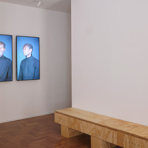 SM22- miart2026 – Milano 
A Brera, la casa torna a farsi mostra: co.arch riallestisce una collezione privata per miart 2026

Ci sono case che nascono finite e case che, invece, continuano a prendere forma nel tempo. La residenza privata progettata da co.arch a Brera appartiene alla seconda categoria: non un interno concluso una volta per tutte, ma un organismo capace di assorbire nuove stratificazioni. Il 18 aprile 2026, in occasione di miart, la casa apre eccezionalmente per un evento privato e diventa il teatro di un nuovo capitolo del progetto: lo studio torna infatti nella residenza milanese realizzata anni fa per i committenti e ne costruisce un secondo tempo, questa volta affidato alla collezione che la coppia ha raccolto. Il punto non è arredare con l’arte, ma verificare come l’arte possa modificare una casa già abitata, già pensata, già sedimentata.
L’intervento lavora soprattutto sulle soglie. All’ingresso della zona giorno, Personal Accounts (Deinde Falase) di Gabrielle Goliath si dispone su tre schermi e trasforma il passaggio in una vera cesura percettiva: non più semplice varco, ma punto di densità emotiva e politica. Il lavoro, parte del più ampio progetto Personal Accounts, usa video e suono per affrontare la normatività globale della violenza patriarcale; collocato in un interno domestico, acquista una tensione ulteriore, perché inserisce nel paesaggio dell’abitare una domanda radicale sul corpo, sulla testimonianza e sull’ascolto. Accanto, Verde di Giorgio Andreotta Calò agisce per contrasto: organico, sospeso, quasi leggero, introduce una contro-misura naturale in un dispositivo altrimenti scandito dalla luce elettronica dei monitor. 
Nel cuore della zona giorno, la scelta più netta riguarda Fritz di Diego Marcon, opera del 2024 realizzata come video in CGI, a colori, con suono e in loop. Co.arch non si limita a predisporre una parete di proiezione: disegna una lunga panca in legno che integra il sistema professionale necessario alla visione e, allo stesso tempo, si presenta come nuovo elemento architettonico. È qui che l’allestimento chiarisce la propria ambizione: l’infrastruttura tecnica non viene nascosta ma diventa parte della sintassi domestica, quasi un dispositivo tra mobile, macchina ottica e scultura d’uso. La materia della panca, in continuità con quelle già impiegate nella casa, richiama anche il lessico degli imballaggi e del trasporto delle opere, come se il collezionismo lasciasse affiorare i propri dispositivi normalmente invisibili. 
Un altro momento decisivo è la grande parete lignea della zona pranzo, dove Situazione con M. di Chiara Enzo compare quasi come un punto di condensazione: un’opera di piccolo formato, ma esattamente centrale rispetto al campo visivo e alla scansione del rivestimento. La sua presenza evita ogni monumentalità, costringendo piuttosto a un gesto di avvicinamento, a una visione raccolta. Sullo sfondo, in una parete della cucina, emerge Minaccia Cavallo di Leonardo De Vito, bassorilievo in terracotta del 2024: un’apparizione laterale, quasi narrativa, che introduce una vibrazione figurativa e tattile dentro una sequenza di spazi misurati con rigore. In mezzo, altre opere di piccolo formato e alcuni interventi fotografici contribuiscono a costruire pause, deviazioni e punti di sosta dello sguardo. 
Nella camera da letto, infine, Noi di Emily Jacir, stampa su tessuto nautico del 2021 nelle dimensioni monumentali di 300 x 300 cm, occupa la parete come un fondale totale. Qui l’opera non è più accento ma atmosfera, non interrompe lo spazio: lo assorbe. La scala del lavoro ribalta quella intima della stanza e fa della superficie tessile una vera architettura visiva, mentre le immagini fotografiche collocate in altri punti della casa mantengono aperto un registro più sommesso, fatto di apparizioni minori e di prossimità. 
Il risultato non assomiglia né a una casa-museo né a una semplice mostra in appartamento. Piuttosto, mette in scena qualcosa di più interessante: l’idea che il progetto d’interni non termini con il cantiere, ma possa riattivarsi quando la vita, le opere e il tempo depositano nuovi significati negli spazi. A Brera, co.arch lavora allora non sull’eccezione spettacolare dell’evento, ma sulla possibilità che una collezione privata trovi finalmente la propria forma domestica. E che una casa, senza smettere di essere casa, impari per qualche giorno a guardarsi come una mostra.


SM22- miart2026 – Milano ENG

In Brera, a Home Becomes an Exhibition Again: co.arch Restages a Private Collection for miart 2026

Article
Some homes are born complete; others continue to take shape over time. The private residence designed by co.arch in Brera belongs to the latter category: not an interior resolved once and for all, but a living structure capable of absorbing new layers. On 18 April 2026, during miart, the house opens exceptionally for a private event and becomes the setting for a new chapter in the project. The studio returns to the Milan residence it designed years ago for the clients and constructs a second act, this time shaped by the collection the couple has assembled. The point is not to furnish the house with art, but to test how art can alter a home that has already been lived in, already conceived, already sedimented.
The intervention works above all through thresholds. At the entrance to the living area, Personal Accounts (Deinde Falase) by Gabrielle Goliath is arranged across three screens, transforming the passage into a true perceptual break: no longer a simple opening, but a point of emotional and political density. Part of the broader Personal Accounts project, the work uses video and sound to address the global normativity of patriarchal violence; placed within a domestic interior, it acquires an added tension, introducing into the landscape of dwelling a radical question about the body, testimony and listening. Beside it, Verde by Giorgio Andreotta Calò acts by contrast: organic, suspended, almost weightless, it introduces a natural countermeasure into a setting otherwise marked by the electronic light of the monitors.
At the heart of the living area, the clearest gesture concerns Fritz by Diego Marcon, a 2024 work made as a CGI video, in colour, with sound, on loop. co.arch does not simply prepare a projection wall: it designs a long wooden bench that incorporates the professional system required for viewing and, at the same time, presents itself as a new architectural element. Here the installation makes its ambition clear: the technical infrastructure is not concealed but becomes part of the domestic syntax, almost a device suspended between furniture, optical machine and utilitarian sculpture. The materiality of the bench, continuous with those already used throughout the house, also recalls the language of packing and transporting artworks, as though collecting were allowing its usually invisible apparatus to surface.
Another key moment is the large wooden wall in the dining area, where Situazione con M. by Chiara Enzo appears almost as a point of condensation: a small-format work, yet placed exactly at the centre of the visual field and of the panelled surface behind it. Its presence avoids any sense of monumentality, instead compelling a gesture of approach, a more intimate way of looking. In the background, on one of the kitchen walls, Minaccia Cavallo by Leonardo De Vito emerges, a 2024 terracotta bas-relief: a lateral, almost narrative apparition that introduces a figurative and tactile vibration into a sequence of spaces measured with rigour. In between, other small-format works and a number of photographic interventions help construct pauses, deviations and resting points for the gaze.
In the bedroom, finally, Noi by Emily Jacir, a 2021 print on nautical fabric measuring 300 x 300 cm, occupies the wall like a total backdrop. Here the work is no longer an accent but an atmosphere; it does not interrupt the space, it absorbs it. The scale of the piece overturns the intimate dimension of the room, turning the textile surface into a true visual architecture, while the photographic images placed elsewhere in the house keep open a quieter register, made up of minor apparitions and proximity.
The result resembles neither a house-museum nor a simple exhibition in an apartment. Instead, it stages something more interesting: the idea that an interior project does not end with construction, but can be reactivated when life, artworks and time deposit new meanings within space. In Brera, co.arch is therefore not working on the spectacular exception of the event, but on the possibility that a private collection might finally find its domestic form. And that a house, without ceasing to be a house, might learn for a few days to look at itself as an exhibition.

CREDITI/CREDITS

Il progetto è stato sviluppato da co.arch studio – Andrea Pezzoli e Giulia Urciuoli 
The project was developed by co.arch studio – Andrea Pezzoli e Giulia Urciuoli 
Architettura / Architecture
co.arch studio
Andrea Pezzoli, Giulia Urciuoli
http://www.coarchstudio.it
https://www.instagram.com/co.arch.studio/

Team di progetto / Project Team
Federica Leonardi
Gaia Uslenghi

Fotografie / Photography
Francesca Iovene
Site- francesca iovene
francesca ióvene (@francescaiovene) • Foto e video di Instagram

Opere

Gabrielle Goliath — Personal Accounts (Deinde Falase), 2024
Giorgio Andreotta Calò — Icarus (ramo) XX
Chiara Enzo — Situazione con M., 2023
Marta Naturale — Finestra, 2024, oil on slate, 18 x 23 cm
Irene Fenara — Supervision, 2024
Diego Marcon — Fritz, 2024
Leonardo De Vito — Minaccia cavallo
Emily Jacir — Noi, 2021 – 300x300 cm

press

https://www.elledecor.com/it/case/a71058280/casa-milano-collezionisti/
