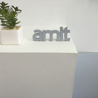 צמח קטן ליד הכתוב amit, על שולחן לבן, עיצוב משרד.