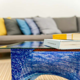 סלון עם ספה ואלמנטים כחולים, ושני ספרים על שולחן זכוכית