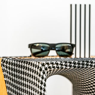 משקפי שמש שחורות על שולחן מודפס שחור ולבן עם תכנון בשילוב ריהוט יחודי