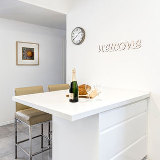 White kitchen island with bottle and the word WELCOME. שדרוג יוקרתי michal-avimor