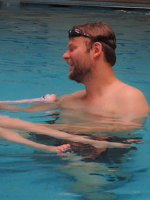 dad is helping his daughter float on her back in the pool