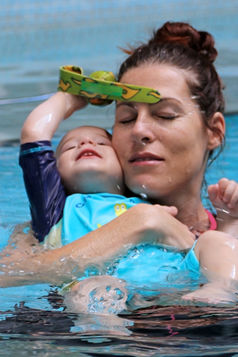 mother holding baby in pool