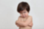 A toddler with dark hair and eyes is crossing his hands pouting while looking straight at the camera