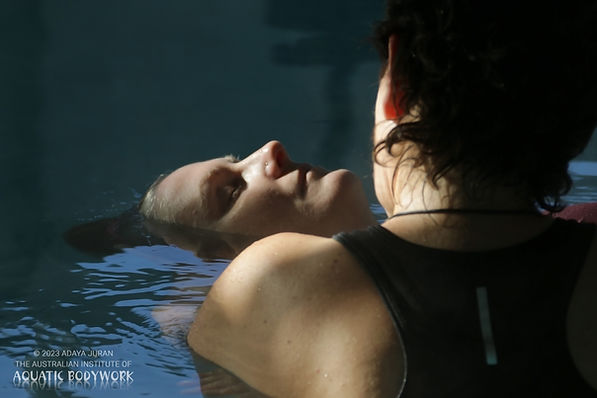 view of a woman's back holding another woman who is closing her eyes and looking calm in s