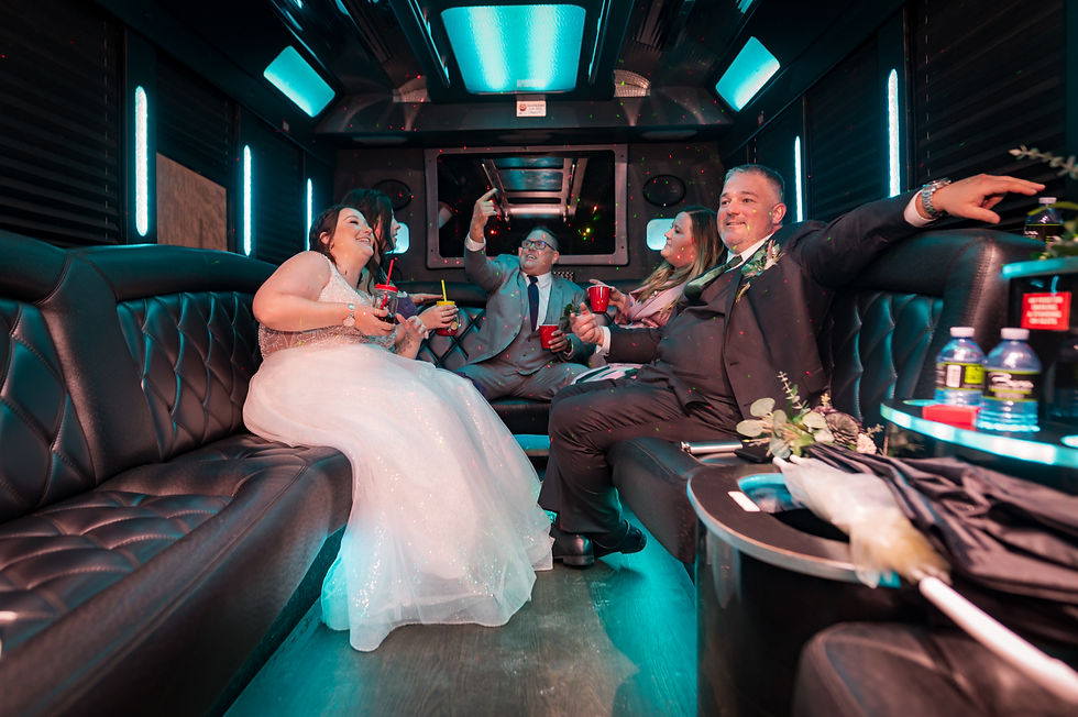 A group of people in formal attire enjoy drinks in a limo with glowing blue lights. A man takes a selfie, creating a festive atmosphere.