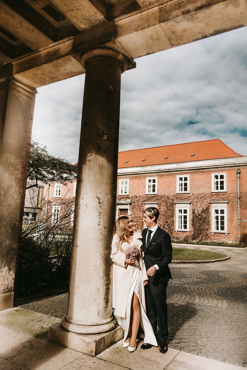 Bride and groom taking posing around brick houses in Copenhagen