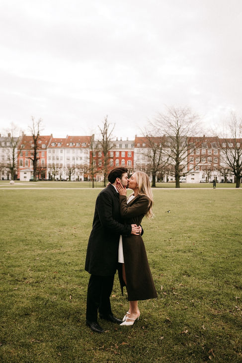 Bride and groom posing elegantly in front of a neoclassical building with statues during their wedding in Copenhagen.