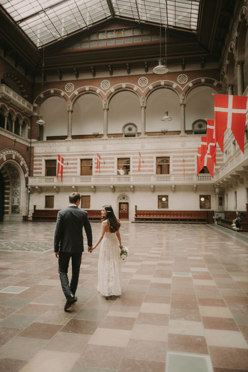 A Bride and Groom walking through the ornate halls of City Hall Copenhagen.