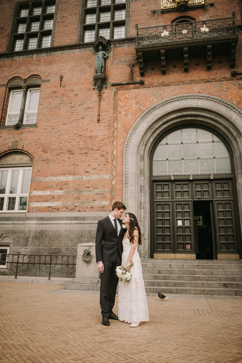 Bride and groom posing together in front of City Hall