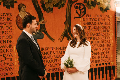 Bride and groom sealing their love with a kiss under the grand arches of Copenhagen City Hall, a testament to their eternal bond.