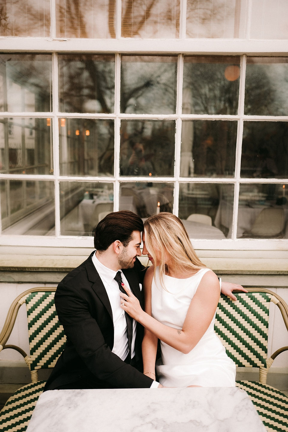 Bride and groom sharing a kiss in front of a statue and neoclassical columns during their wedding in Copenhagen.