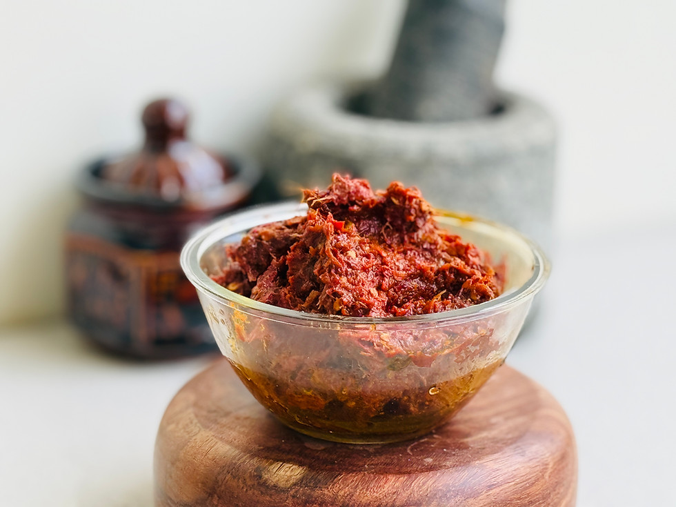 A deep red, menacingly intense Korivikaram pickle in a small tasting bowl.