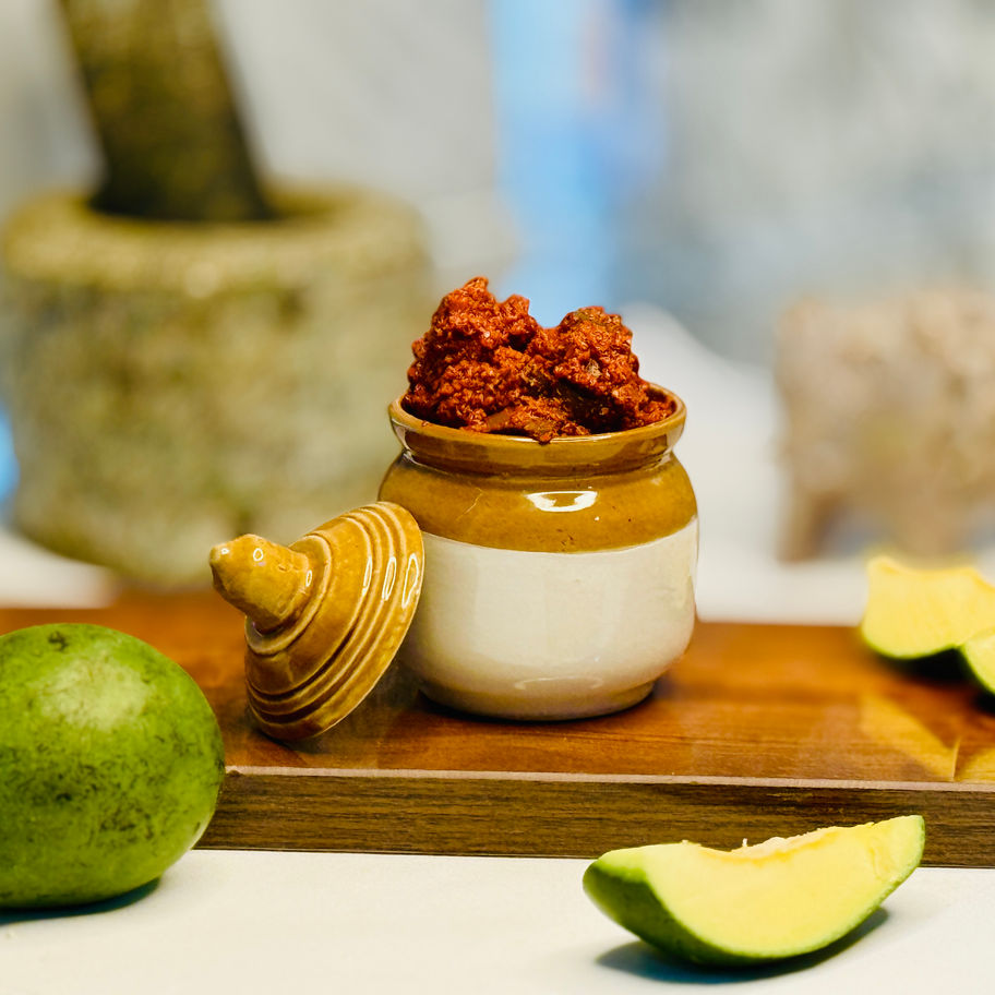 A bowl of authentic Mamidikaya Avakaya pickle with fresh raw mangoes.