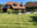 Large open garden with green grass and a bungalow house