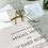 Thumbnail: clear acrylic wedding invitation with black text and a gold mirror monogram