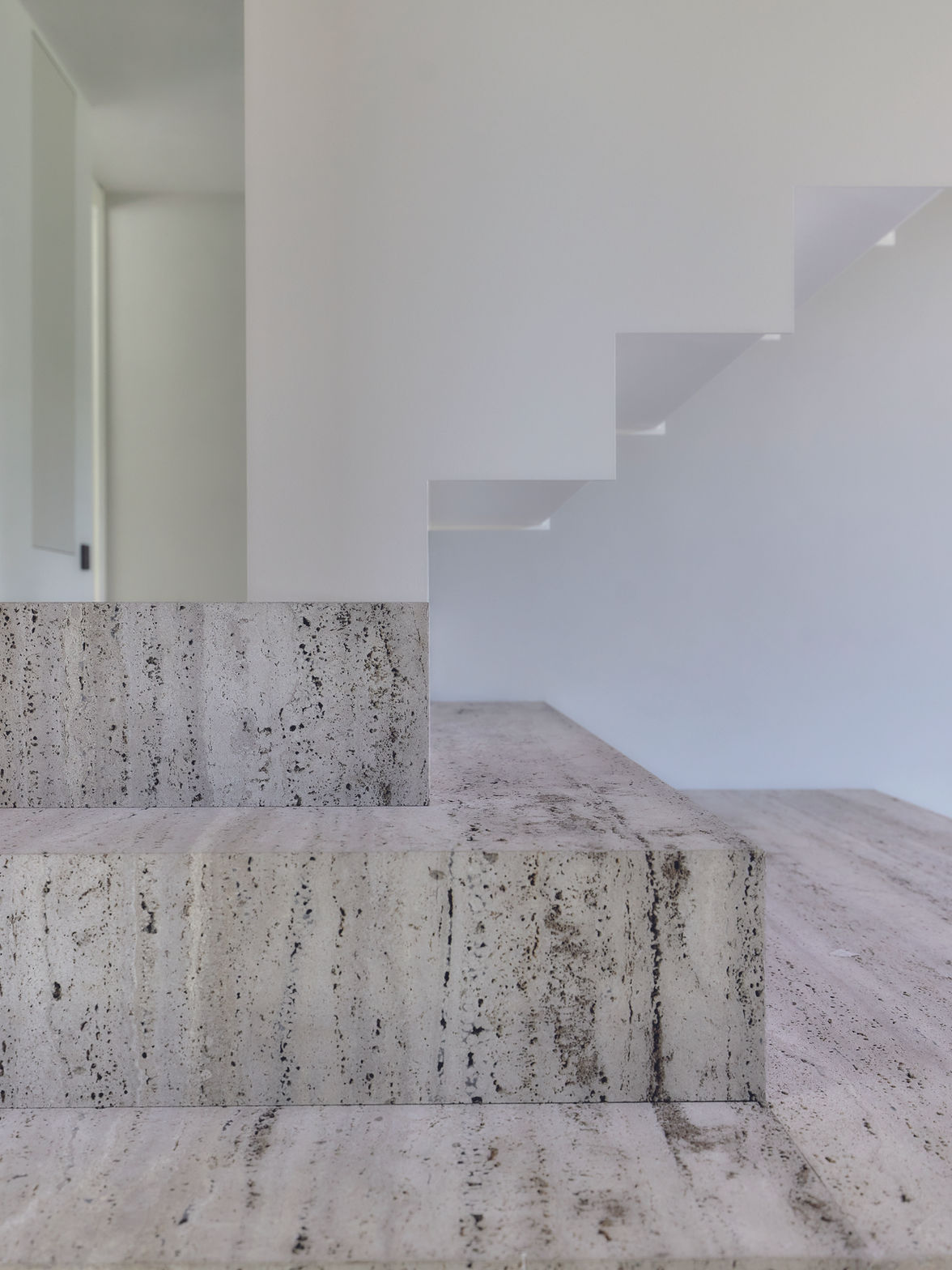 Sculpturale trap in travertin en metaal met natuurlijke lichtinval en minimalistische afwerking - Sjiek mo peur, België