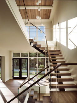 Great Falls Farm staircase with floating wooden steps, glass railings, double-height windows and nat