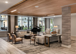 Modern lobby with wood ceiling, piano, and cozy seating overlooking large windows
