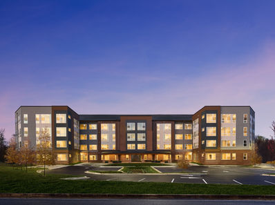 Modern apartment complex at dusk with illuminated windows and clean landscaping