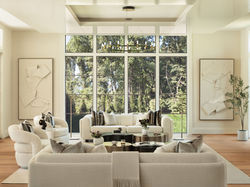 Modern living room with large glass wall and cozy white seating facing the view