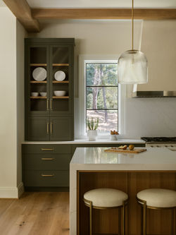 Kitchen corner with olive cabinets, island seating, and pendant lighting
