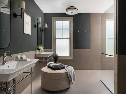 Modern bathroom with dual vanities, ottoman, and walk-in glass shower