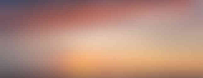 Orange sunset turns amber and purple in the sky with fading light glinting on the ocean beneath