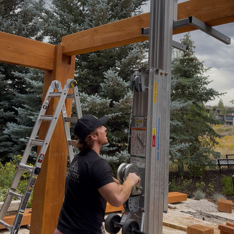 Professional carpenter raising a heavy timber fire-resistant structural beam for an architectural pergola project in Orange County, Southern California.
