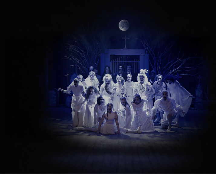 espetáculo de teatro a familia addams, com atores vestindo branco olhando para frente com uma luz azul de cima