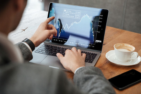 cropped-image-of-businessman-sitting-by-the-table-in-cafe-and-analyzing-indicators-on-lapt