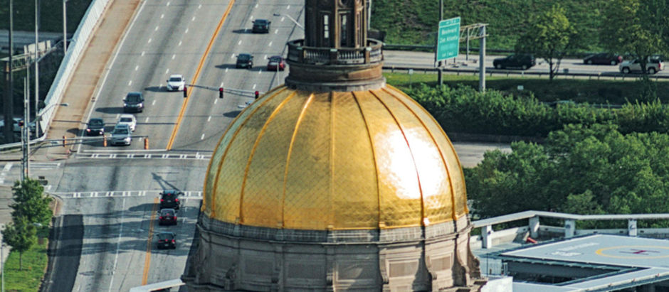 Daytime view of the Georgia State Capitol building in downtown Atlanta featuring the iconic historic gold dome against a clear sky.