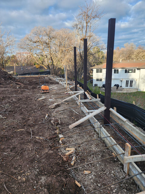 Trex post for a Trex fence set inside a footing that supports a variable height wall.