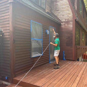 Aaron is spraying paint brown stain for an exterior painting project in Andover CT