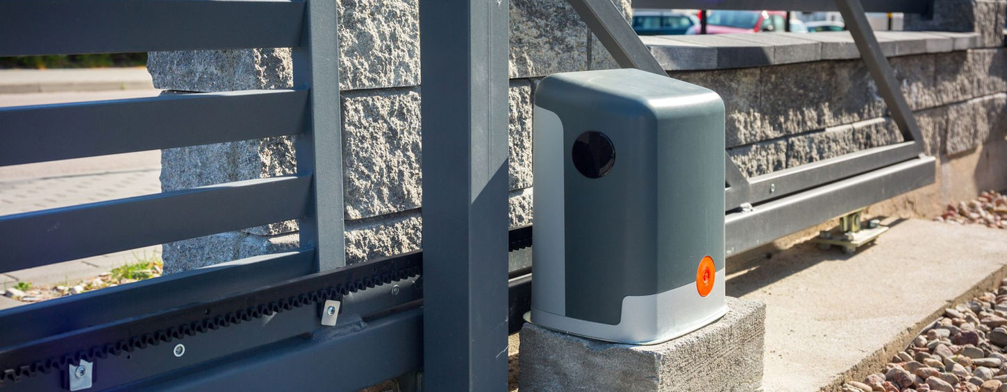 close-up of an automatic sliding gate motor and track system with a modern design installed next to a stone wall.