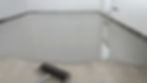 floor coating spread across a concrete floor with a roller in the corner