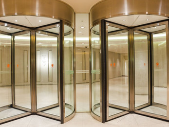 two revolving doors with a sleek, modern design inside a well-lit lobby or building entrance.