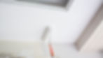close-up of a paint roller applying white paint to a ceiling