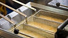 commercial deep fryer baskets with hot cooking oil in busy restaurant kitchen environment
