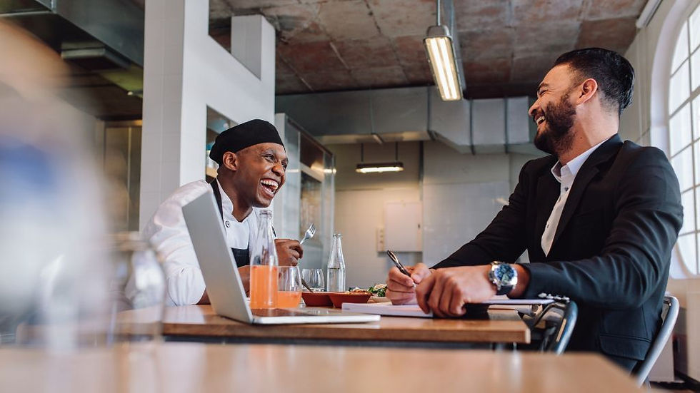 happy restaurant owner and employee working together inside a commercial restaurant kitchen