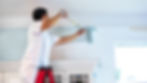 contractor on a ladder appliing blue interior paint to a wall