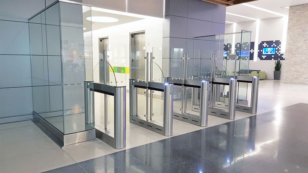 stainless steel optical turnstiles with glass barriers in a modern office lobby.